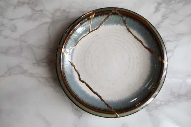 A kintsugi bowl - broken ceramic repaired with gold, embodying the Japanese philosophy of wabi-sabi: finding beauty in imperfection